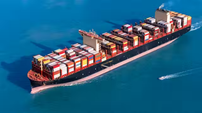 Red container ship travelling on ocean - Image by Getty images co